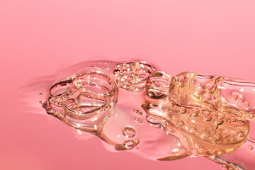 Spilled transparent golden yellow bubbly gel close-up. Leaking out of the pipette.  In pink tones