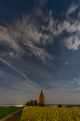 Full moon illuminated rapeseed fielt with old watchtower in the background. taken around midnight