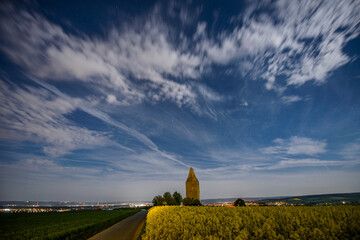 Full moon illuminated rapeseed fielt with old watchtower in the background. taken around midnight