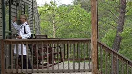 Fototapeta premium Medium view of mature woman doctor or nurse making a house call home visit in a rural area.