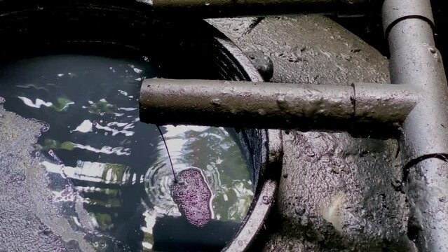 Black chemical wastewater coming out from pipe to storage tank from industrial processes. Hazardous and toxic waste - WWTP Wastewater Treatment Procedure