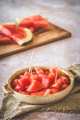 Pieces of watermelon as finger food on a plate, sliced watermelon in the background