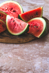Eighths of a watermelon on a wooden plate on beige structured background