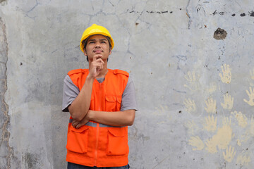 Man construction worker touches chin, looking up, thinks over new idea for building, works as...