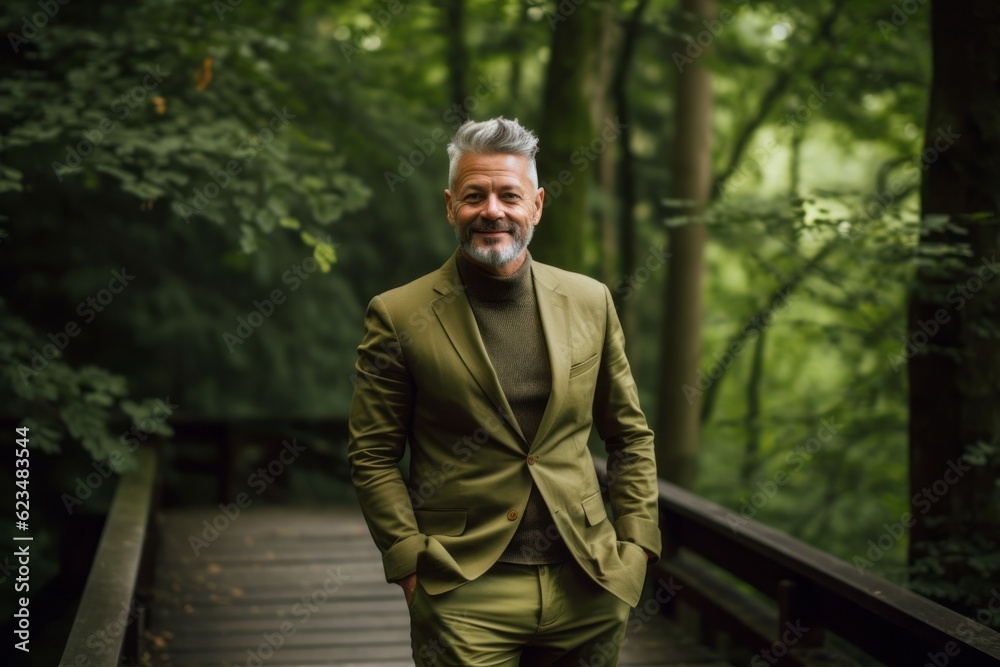 Wall mural Urban fashion portrait photography of a glad mature man wearing a chic jumpsuit against a moss-covered forest background. With generative AI technology - Wall murals