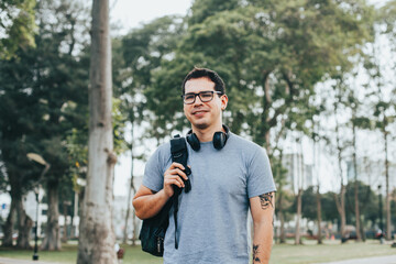 Portrait of young student with glasses and backpack in an outdoor park. Concept of people.