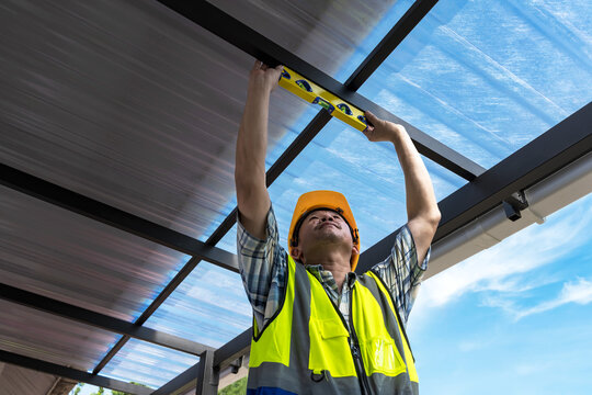 Builder man using water level tool working with roof installation in construction site