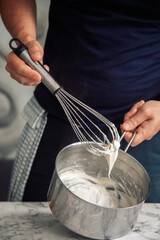 chef holding a white béchamel sauce on a whisk
