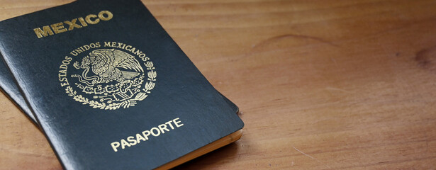 Two Mexican passports on a wooden table, copy space.