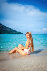 Fototapeta premium Woman in swimwear enjoys the tropical beach with turquoise water, embracing the beauty of Thailand vacation. Concept of travel and summer vacation.