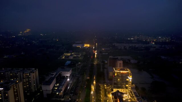 aerial drone shot of brightly lit shopping mall 3 reach roads elan epic in gurgaon at blue hour with shops, food places offices, homes at blue hour dusk with flooded streets