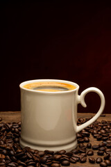 Black coffee or hot tea in a cappuccino espresso cup, breakfast food with coffee beans on a wooden table Isolated on a dark background, top view