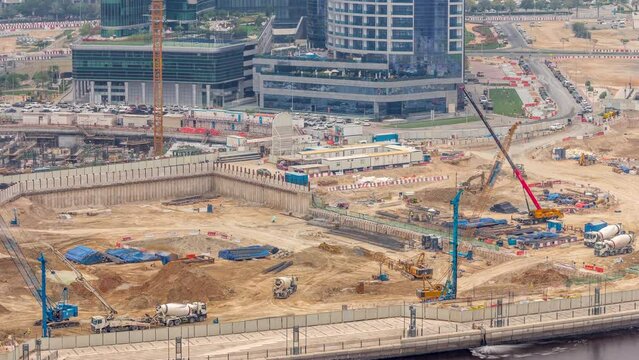 Foundation pit for construction of apartment complex building aerial timelapse. Deep installation and excavation with heavy machinery as excavator, cranes, bulldozer, concreete mixer and trucks, Dubai