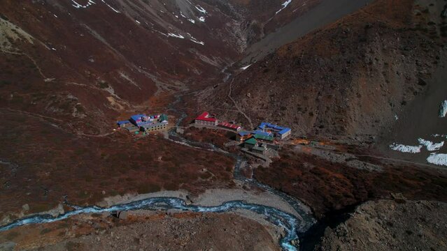 Aerial overhead ascending view Tilicho base camp red blue rooftop hotel buildings complex in Manang district. Annapurna circuit trekking. Himalayas mountains hotels tours concept.