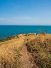 Landscape summer front view on outdoor hill side with grass blue water calm waves, cool breeze, and clear sky. Suitable relaxation and travel On holiday Khao Laem Ya National Park Rayong, Thailand