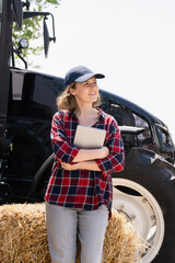 Woman farmer with a digital tablet on the background of an agricultural tractor