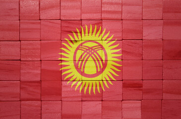 colorful painted big national flag of kyrgyzstan on a wooden cubes texture.
