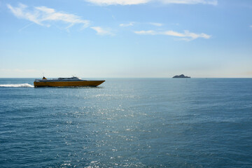 A large sea pleasure ship sails on the sea to the right. A small island in the distance. A picturesque sea voyage