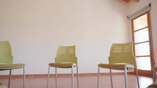 green chairs arranged in a circle for a group discussion inside a bright room with wooden roof