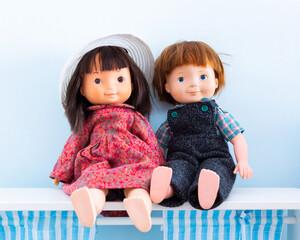 Horizontal view of vintage boy and girl dolls dressed in handmade clothes displayed sitting on shelf