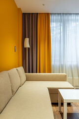 beige sofa against the background of yellow and brown curtains, yellow wall