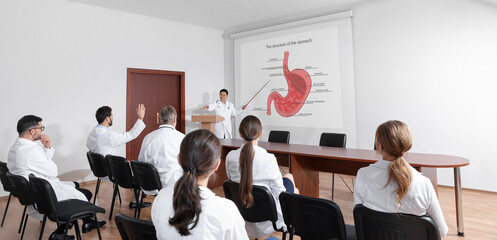 Lecture in gastroenterology. Professors and doctors in conference room. Projection screen with structure of stomach - obrazy, fototapety, plakaty