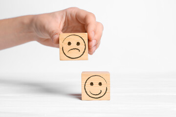 Complaint. Woman choosing wooden cube with drawn sad face instead of another one with happy on...