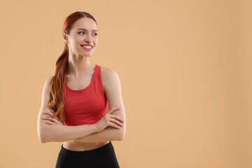 Young woman in sportswear on beige background, space for text