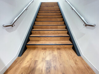 The staircase steps are made of brown wood and have stainless steel handrails on both sides.