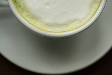 Top view white cup of hot green tea latte on wood background in restaurant.Top view with copyspace for your text.