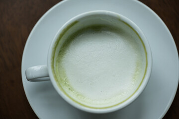Top view white cup of hot green tea latte on wood background in restaurant.Top view with copyspace for your text.