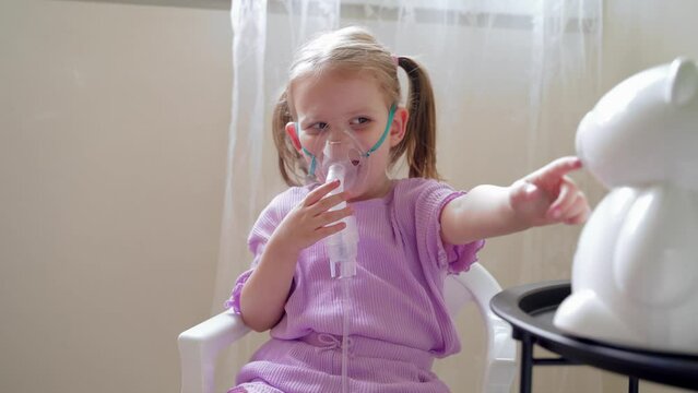 Cute little little girl inhaling mist from nebulizer at home 