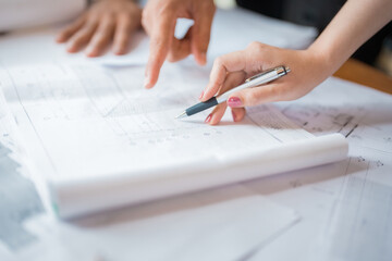 Close-up of a female engineer hand with pink nails and a hand of a male engineer or architect next...