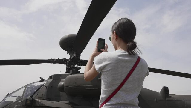 Young woman take pictures from Apache attack helicopter chopper on display at the Army Aviation Centre
