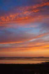 Fototapeta premium sunset sky with reflections in water, sunlight and colored orange clouds. Magnificent view of the sea and sun in evening. travel and freedom, meditation, poster. amazing sunset light on ocean