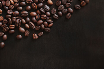 Roasted coffee beans on a wooden dark table, top view. Background of fragrant brown coffee beans...