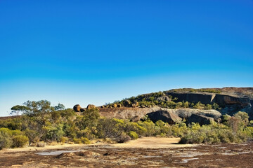 Eroded rocks and boulders with stunted outback vegetation in  Sandford Rocks Nature Reserve, a granite outcrop near Westonia, Western Australia.
