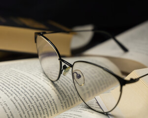 New paperback books, diary, fanned pages on wooden desk table and grunge background Daylight. Books stacking. Back to school. Copy Space. Education background, Reading background, glasses on book.