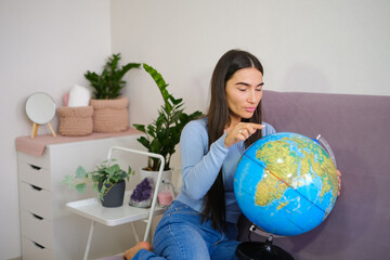 Traveling concept, Asian beautiful woman looking at globe ball in the bright room. High quality photo