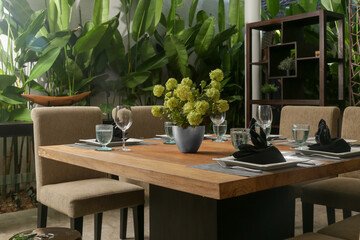 Massive wooden dining table with beautiful flower centerpiece on the balcony