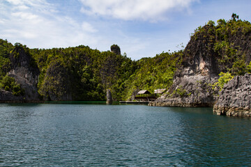 Fototapeta na wymiar Huts and a pier in a bay of the national park of Raja Ampat, Indonesia