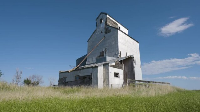 Blue Skies And Wooden Grain Elevator In Grassy Filed