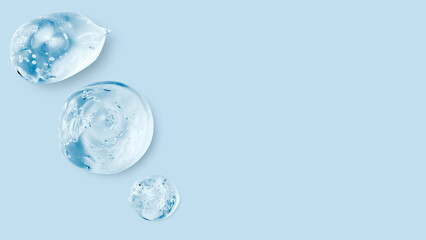 Drops and smears of a transparent gel or serum on a blue background. Banner with empty space for advertising.
