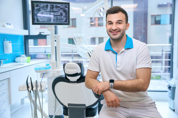 Smiling man sitting at the workplace in the dental office