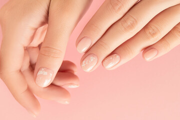Womans hands with trendy nude manicure on pink background. Summer nail design
