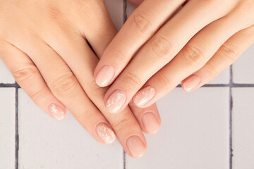 Beautiful womans hands with nude nail design on white background. Manicure, pedicure beauty salon concept