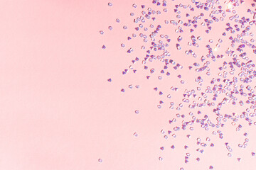 Fototapeta premium Small silver crystal confetti on a pink background. Shiny concept with copy space.