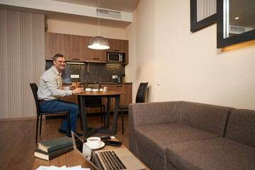 Happy man having breakfast in hotel room
