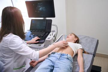 Obraz na płótnie Canvas Female doctor conducts an ultrasound of the internal organs of a little girl