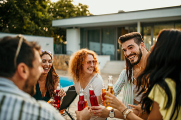 A large group of people gather around a poolside, pouring their favorite cocktails from the bottles and enjoying the refreshing beverages.
